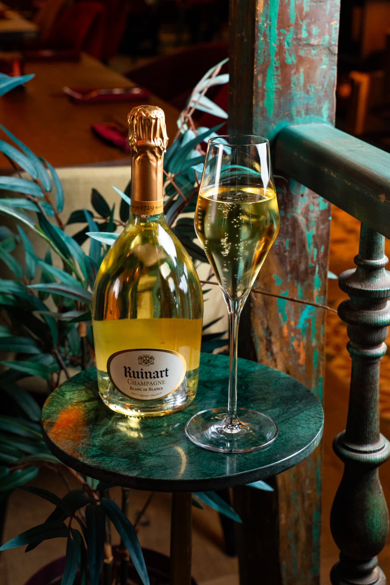 Fles champagne met een gevuld glas op een bijzettafeltje