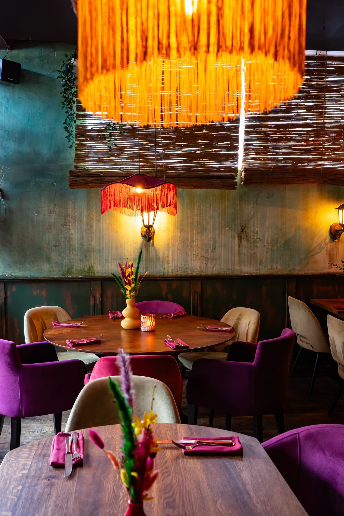 Gedekte ronde tafel onder een oranje franjelamp bij Latinos